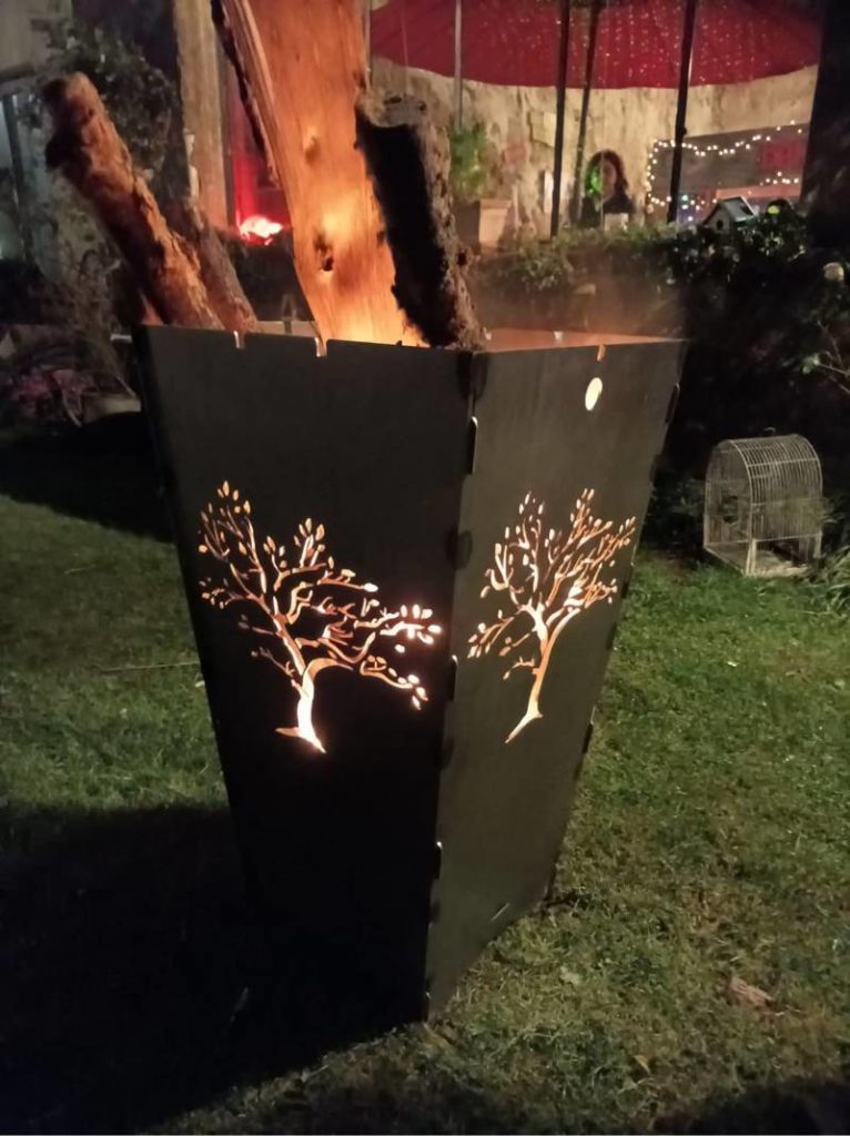 un brasero lanterne qui a des buches de bois enflammée avec une décoration d'arbre